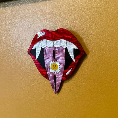 Decorative wall art of a stylized mouth with a sad face on a beige wall.