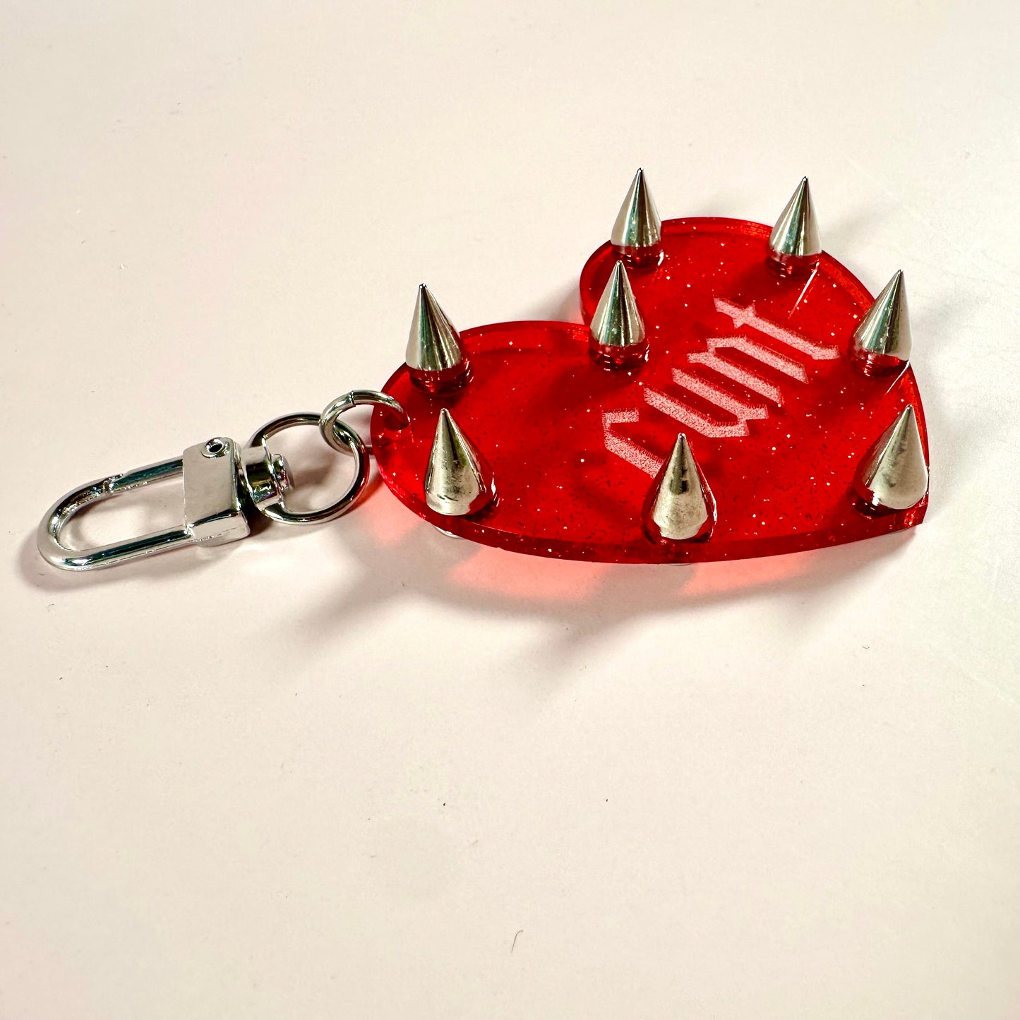 Red heart-shaped keychain with silver spikes on a white background