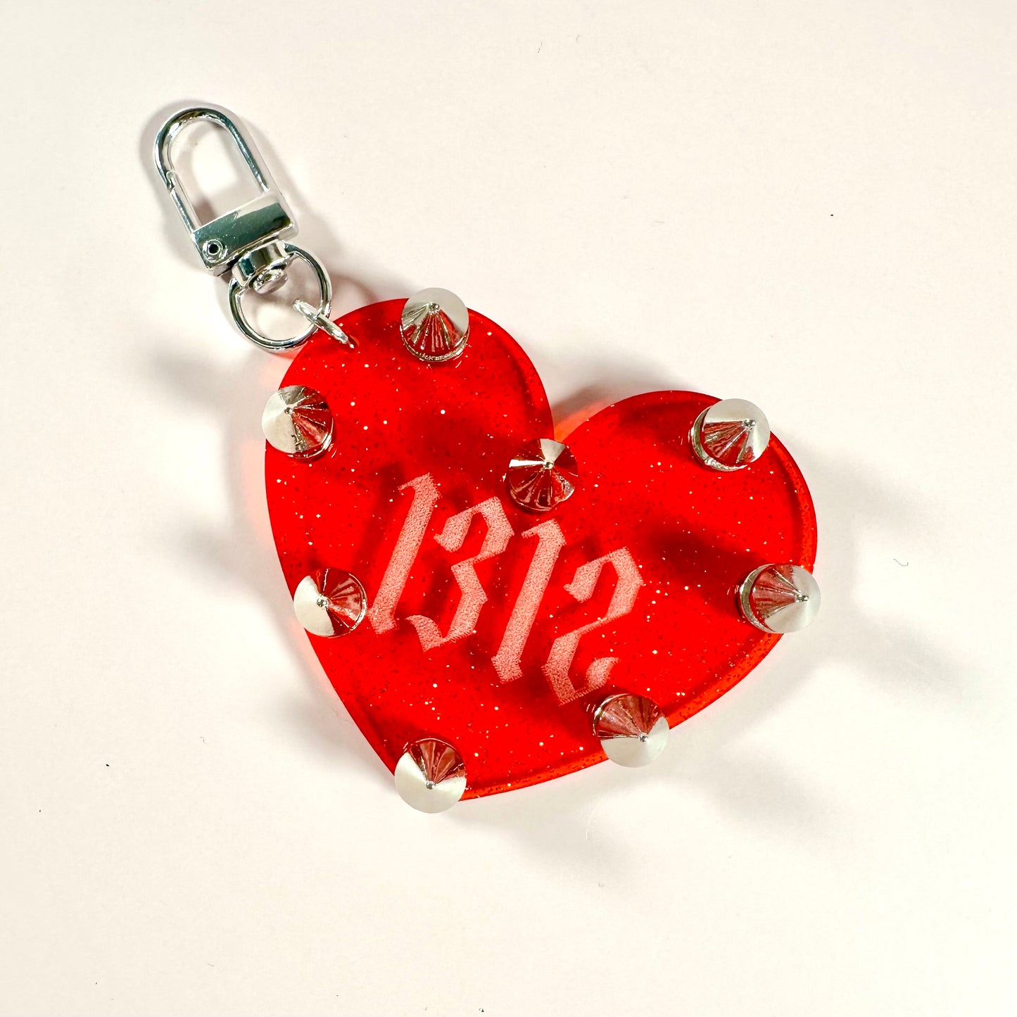 Red heart-shaped tag with '1312' printed on it, attached to a metal clasp.