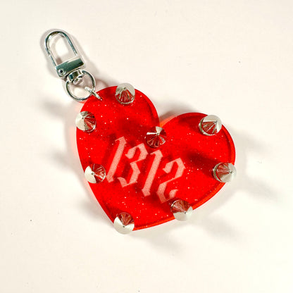 Red heart-shaped tag with '1312' printed on it, attached to a metal clasp.