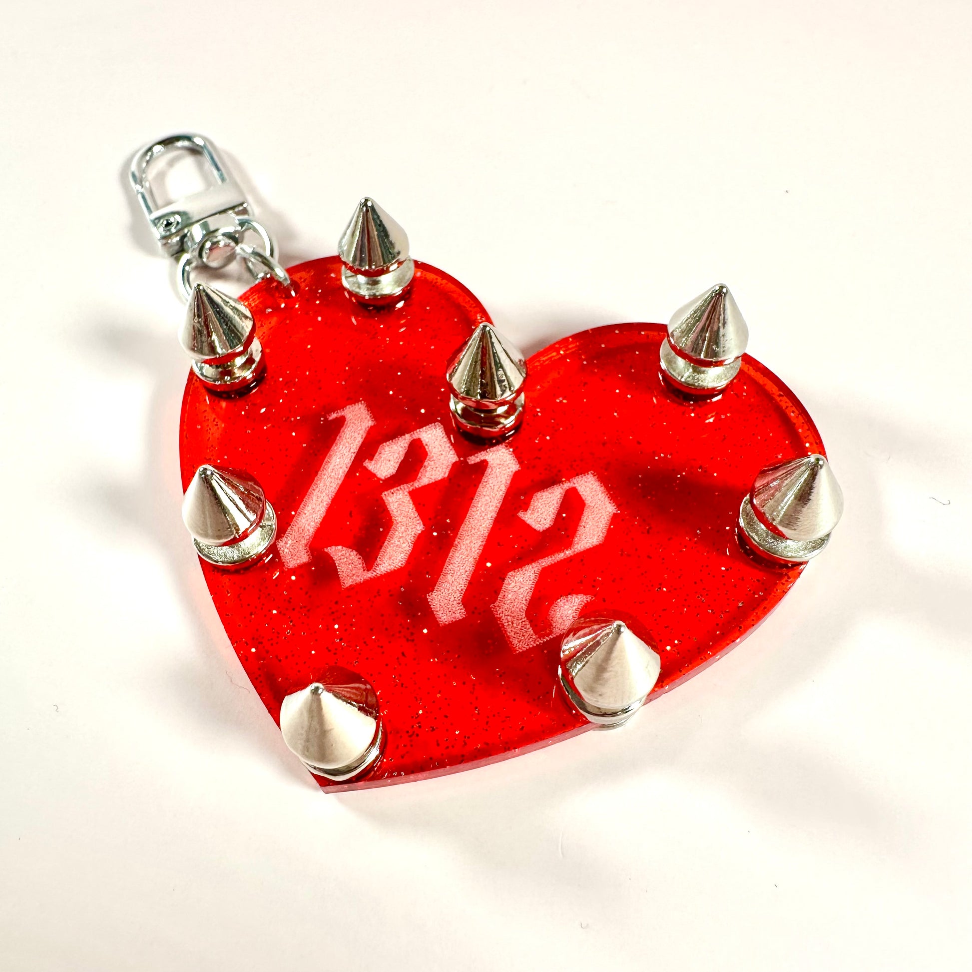 Red heart-shaped keychain with silver spikes on a white background