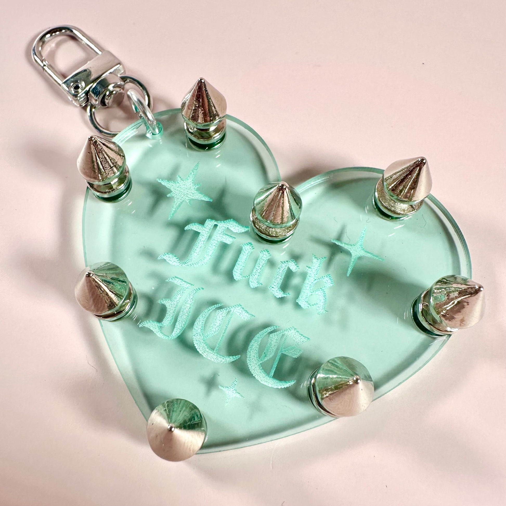 Heart-shaped keychain with studs and 'Truck Face' engraving on a light pink background