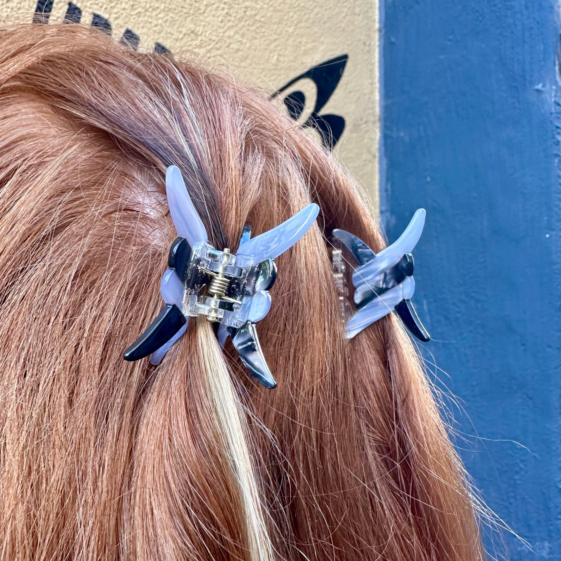 Person wearing a hair clip with a blue and black design on a plain background