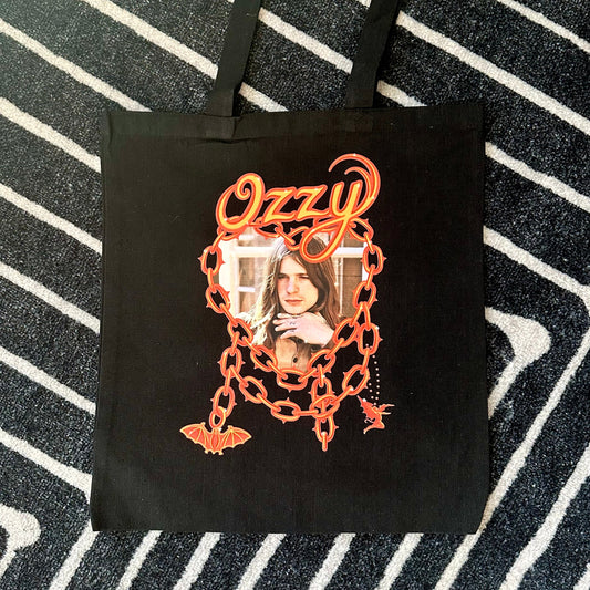 Black tote bag with 'Ozzy' design on a striped background