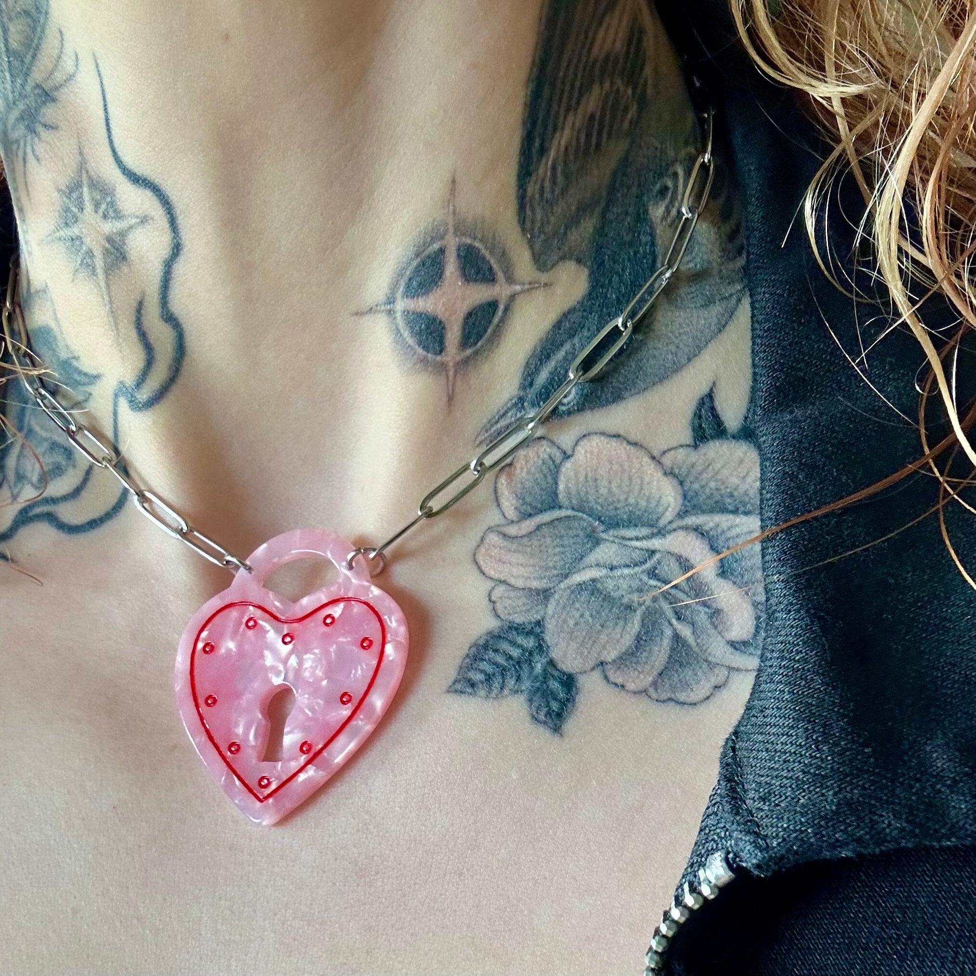 Necklace with a pink heart-shaped pendant on a tattooed neck