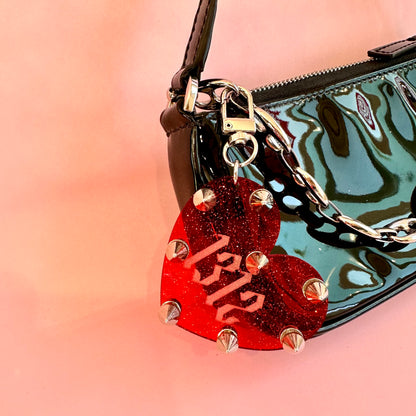 Red glittery heart-shaped keychain with '1312' on a reflective surface