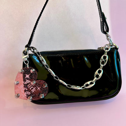 Black handbag with a chain handle on a light pink background
