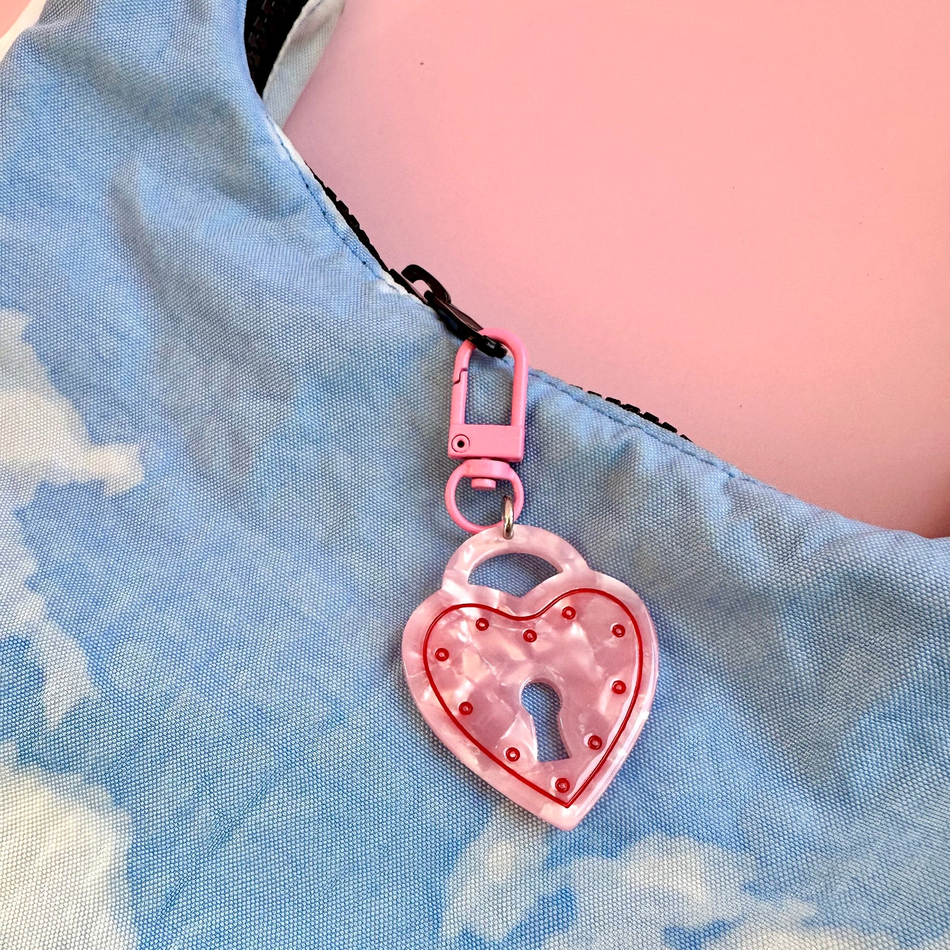 Pink heart-shaped keychain with a lock design on a blue denim background