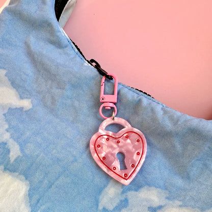 Pink heart-shaped keychain with a lock design on a blue denim background