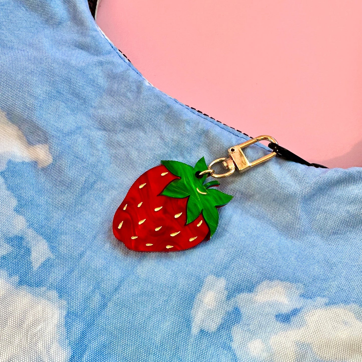 Strawberry-shaped keychain on a blue fabric background