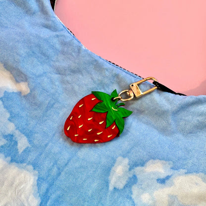 Strawberry-shaped keychain on a blue fabric background