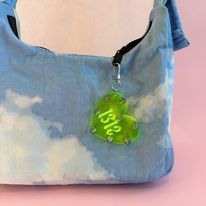 Heart-shaped green tag with '1312' on a blue tie-dye bag against a pink background
