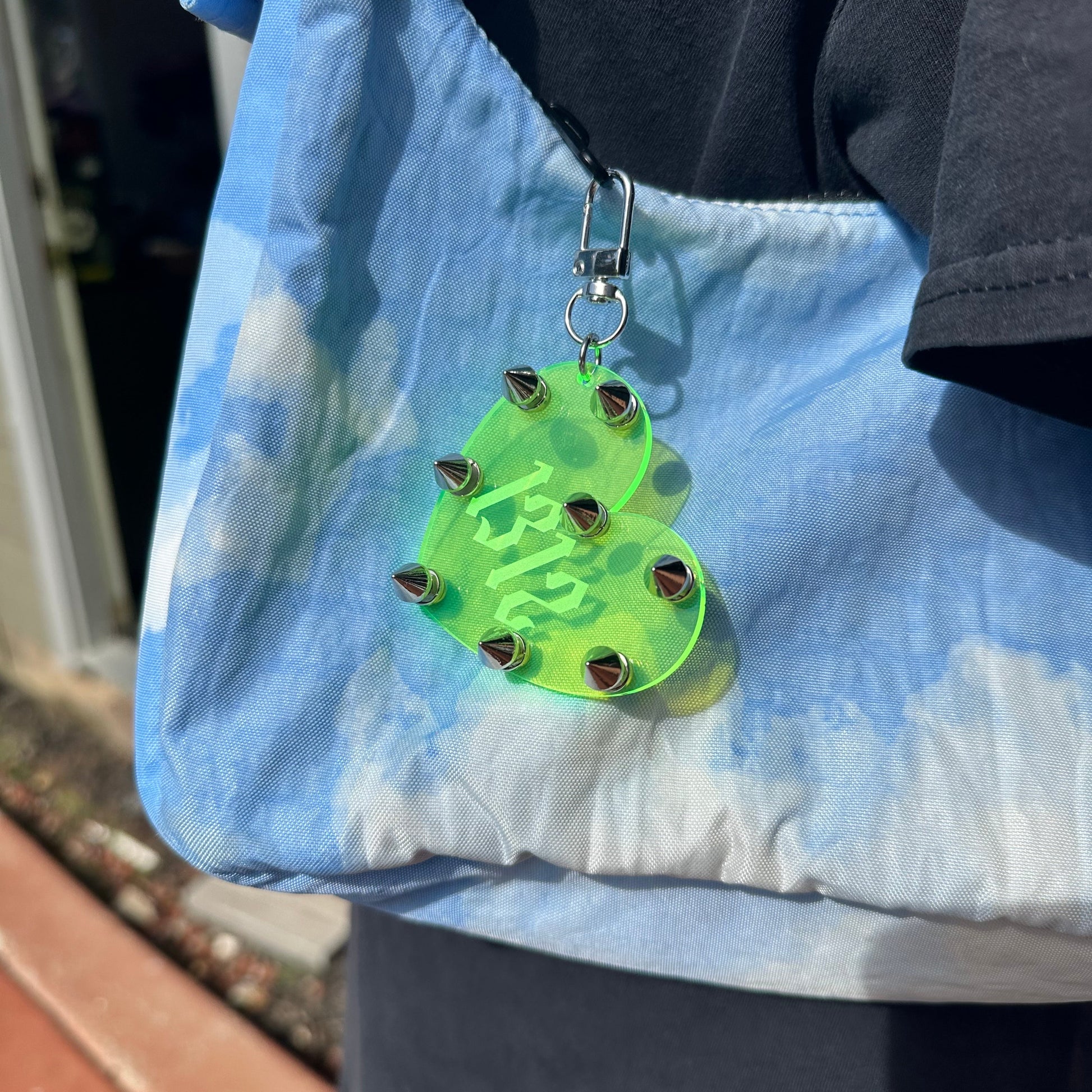 Green heart-shaped keychain with '1312' on a blue fabric background
