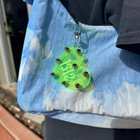 Green heart-shaped keychain with '1312' on a blue fabric background