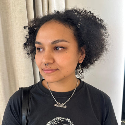 Person wearing a black t-shirt with a graphic design, standing indoors against a neutral background.