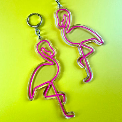Two flamingo-shaped earrings with silver metal rings, featuring a hot pink outline on a bright yellow background.
