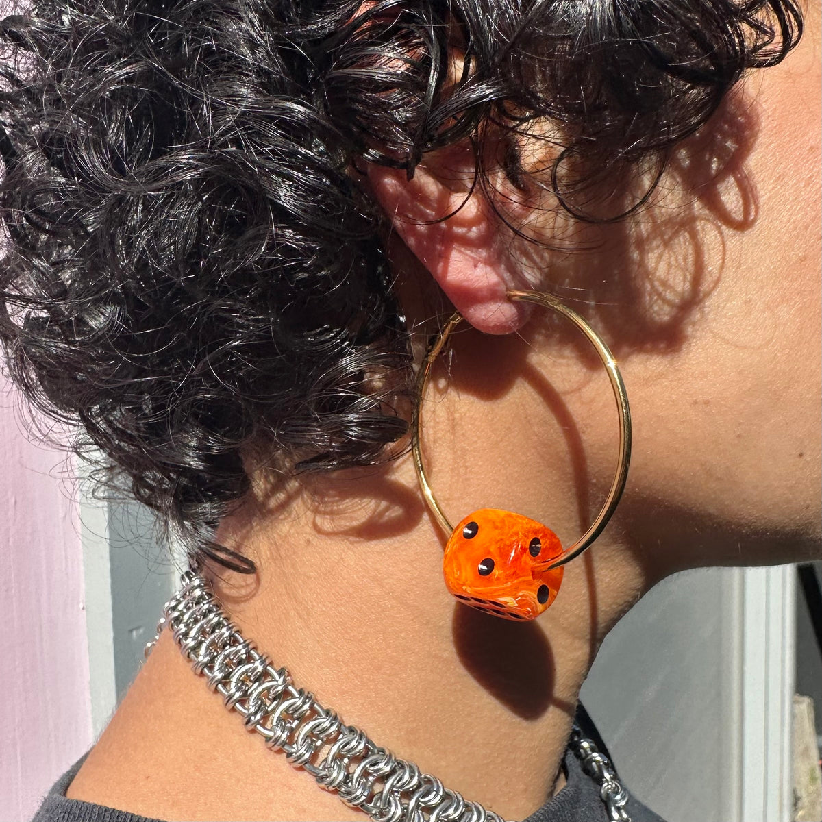 Person wearing a gold hoop earring with an orange bead, close-up shot.