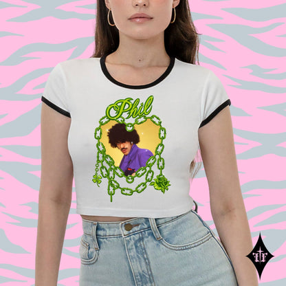 Person wearing a white t-shirt with a graphic design and text, standing against a pink and gray patterned background.