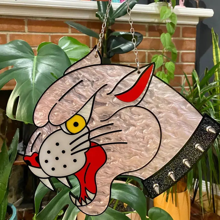 Decorative cat-shaped object with a chain, surrounded by plants.