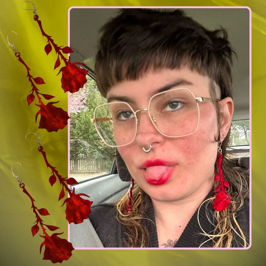 Person wearing red rose earrings with a green background and text 'Hanging Rose Earrings'.