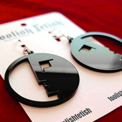 Black circular earrings on a 'foolishletish' branded card with a red background