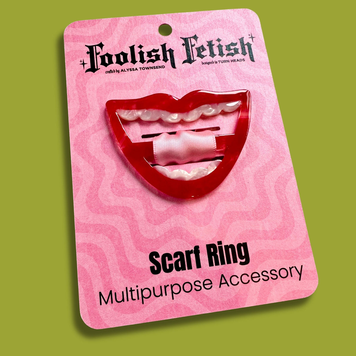 red smile scarf ring on a pink psychedelic card that says Foolish Fetish and scarf ring on a green background