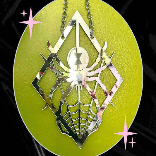 Metallic spider web pendant on a green circular background with decorative stars.