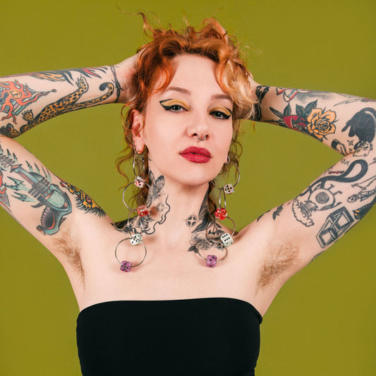 Woman with tattoos and piercings posing against a green background