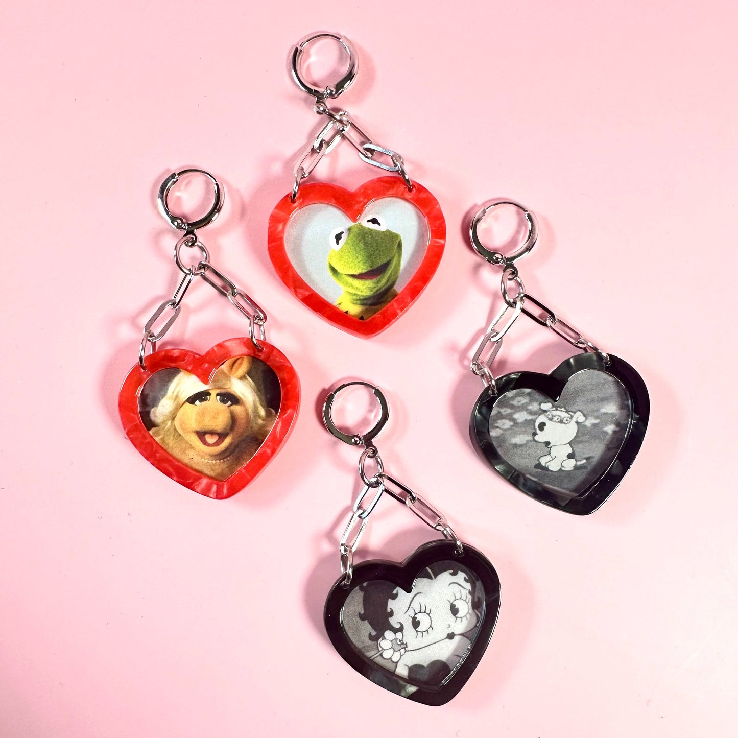 Heart-shaped keychains with cartoon characters on a pink background