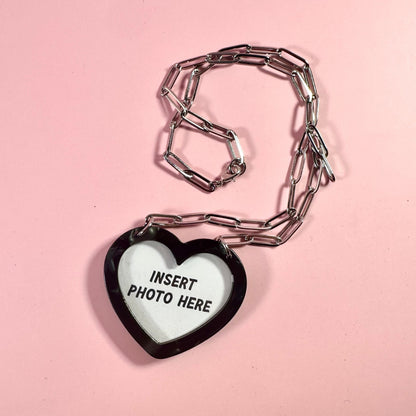 Heart-shaped photo frame charm on a pink background