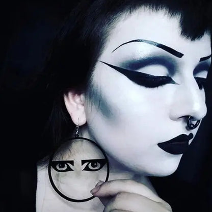 Person with dramatic makeup holding a circular mirror with similar design.