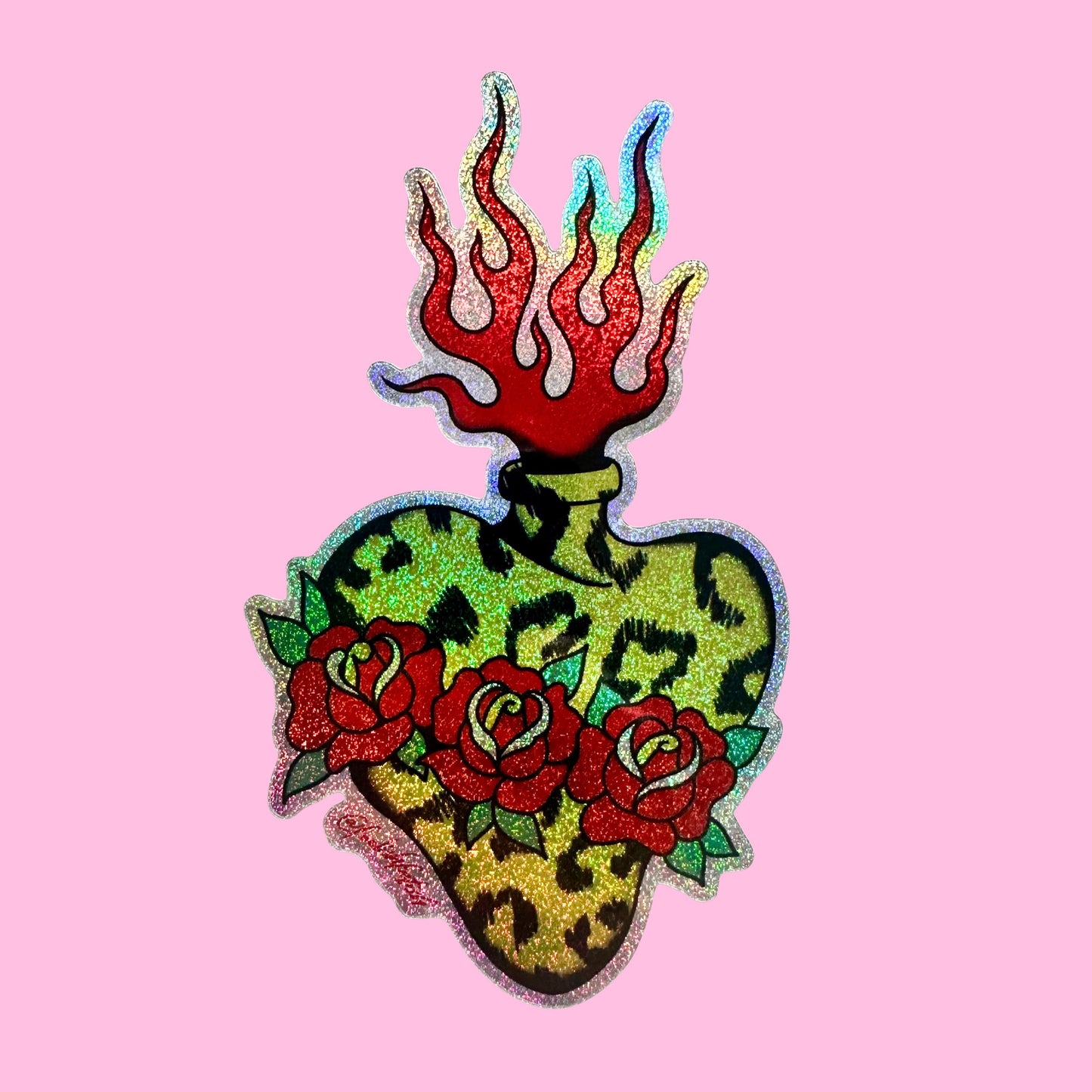A decorative heart-shaped patch with a leopard print pattern, red roses, and red flames on top, shown on a solid pink background.