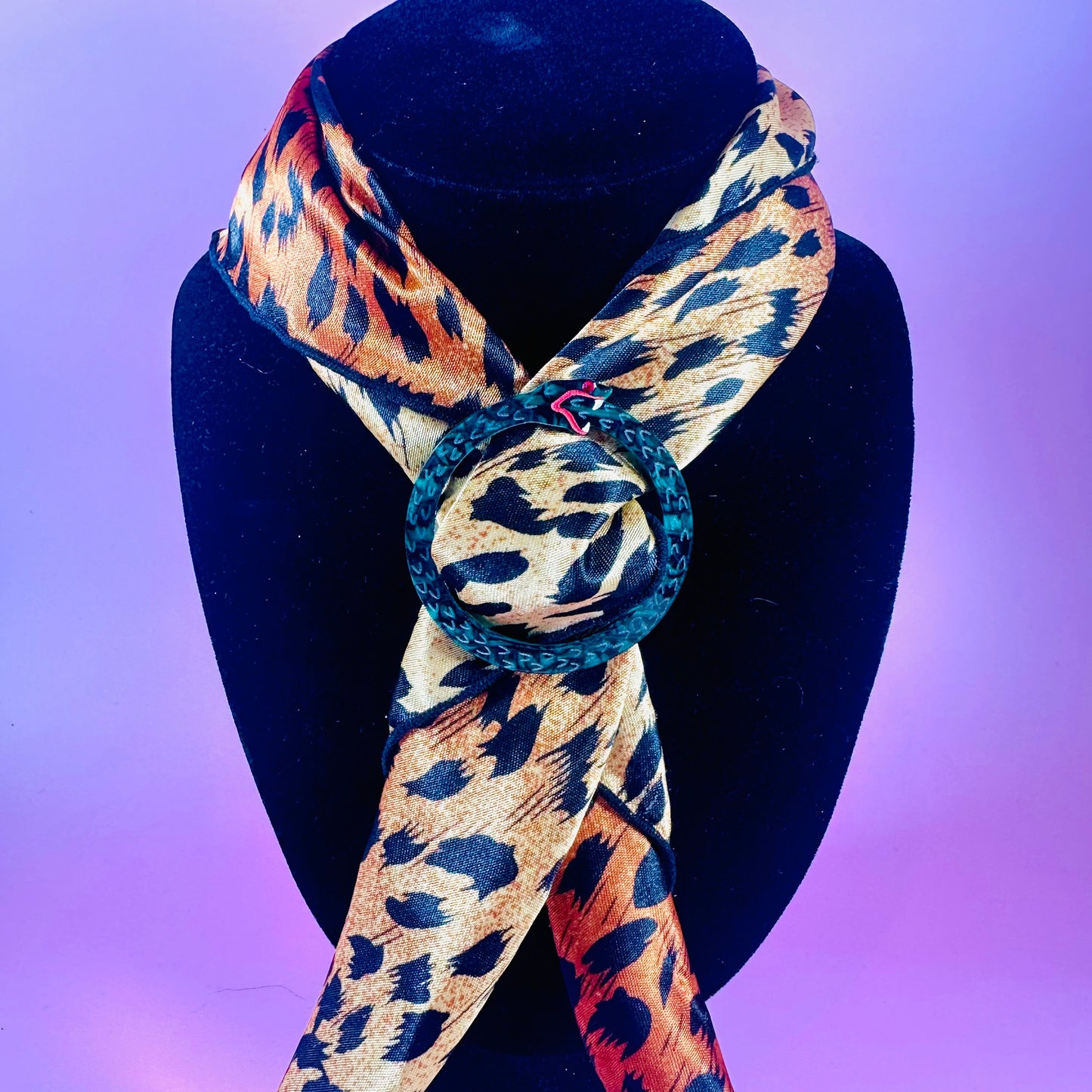 Leopard print scarf with a knot on a black mannequin against a purple background