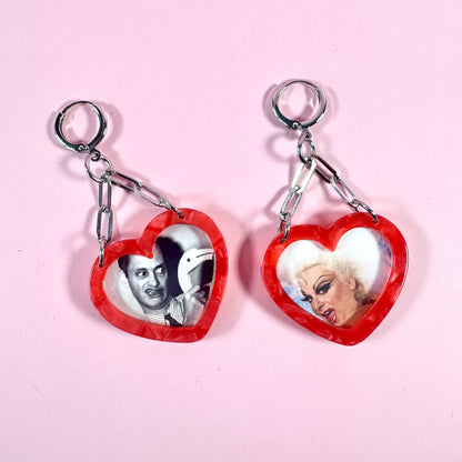 Heart-shaped keychains with images of people on a pink background