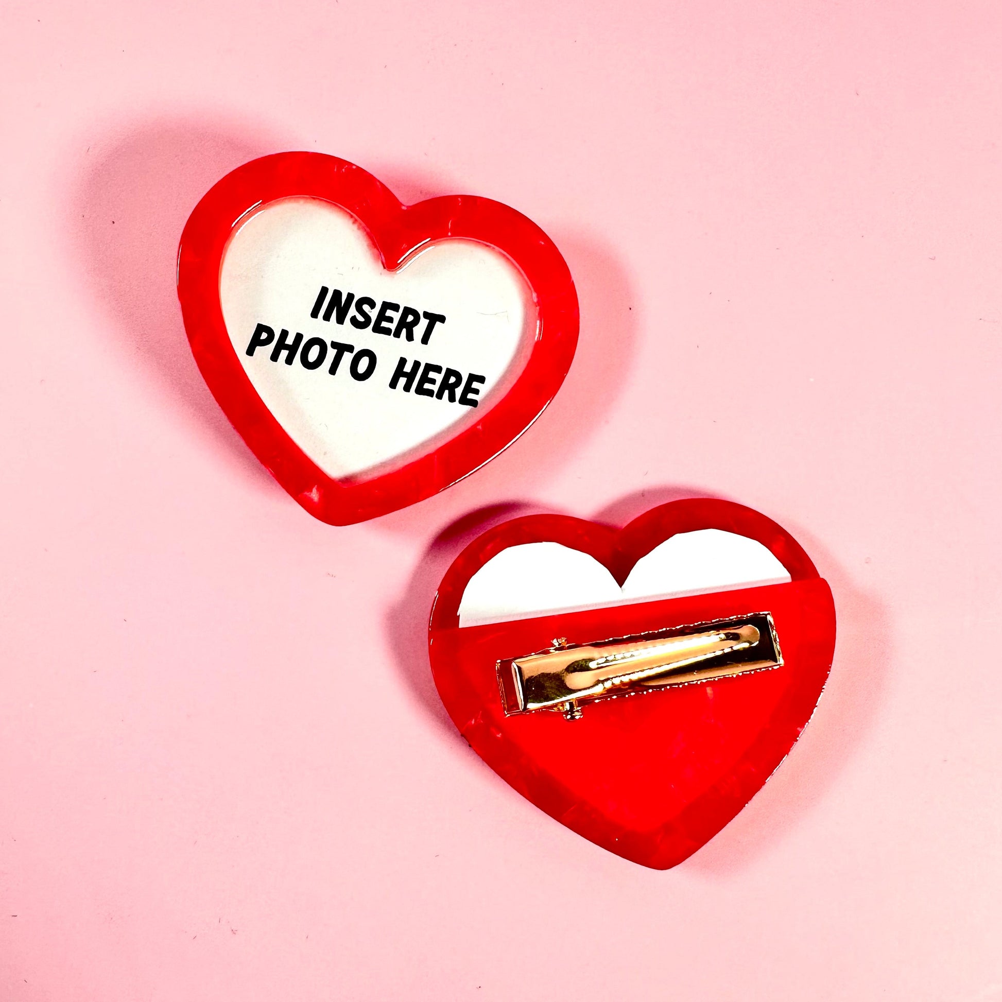 Red heart-shaped frame with a gold clip on a pink background