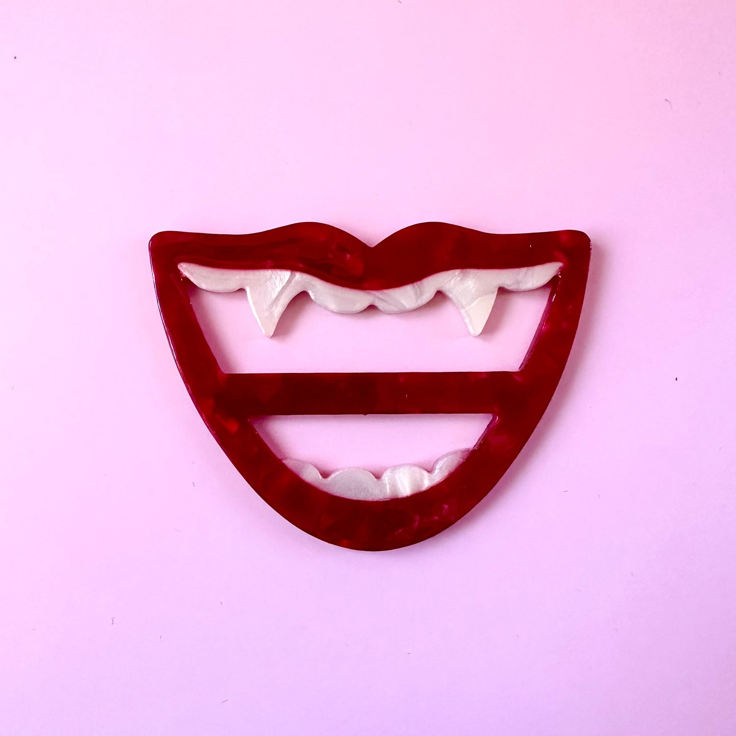 red mouth with fang scarf ring buckle on pink background